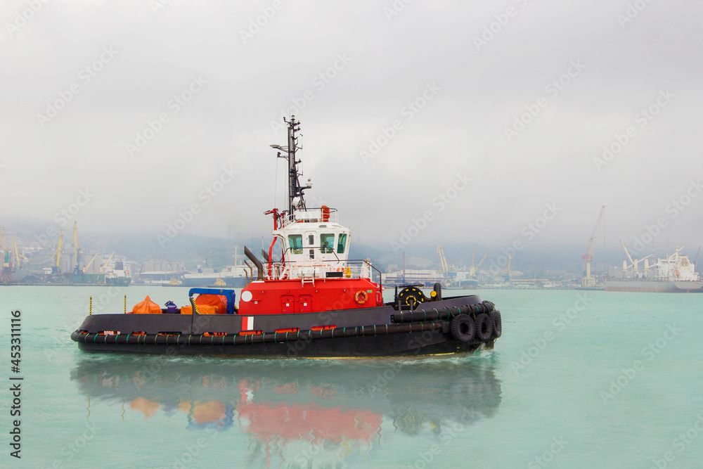 Tugboat on maneuvers at sea.Offshore supply boat in a calm weather day.Logistic import export and transport industry background. Tugboat on maneuvers at sea.Offshore supply boat in a calm weather day.Logistic import export and transport industry background.