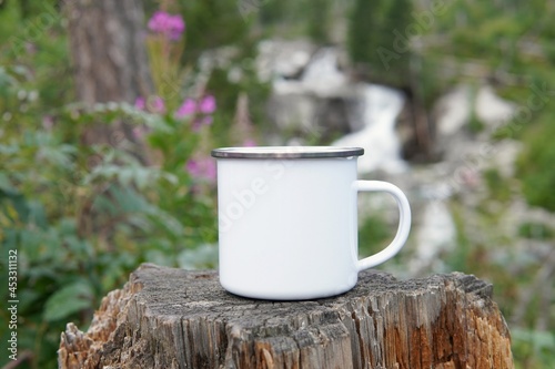 Blank enamel coffee cup mockup, empty camping mug in forest for design presentation, photo