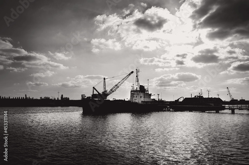 Grayscale shot of an industrial ship in water under the sunlight photo