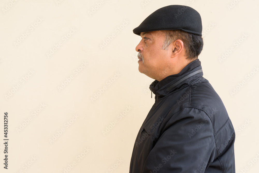 Portrait of handsome Indian man with mustache wearing hat against plain wall Portrait of handsome Indian man with mustache wearing hat against plain wall