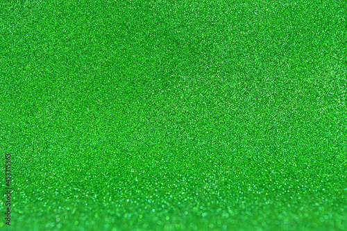 Background from green glitter foamiran with a bend. Brilliant bokeh. Festive decoration. Christmas pattern. Design element