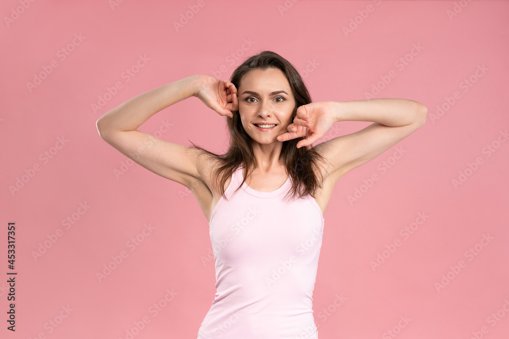 Charming young woman holding hands up with no makeup, skin care concept, attractive brunette girl in pink t-shirt on pink background. Human emotions, facial expression concept. Beauty concept. Charming young woman holding hands up with no makeup, skin care concept, attractive brunette girl in pink t-shirt on pink background. Human emotions, facial expression concept. Beauty concept.