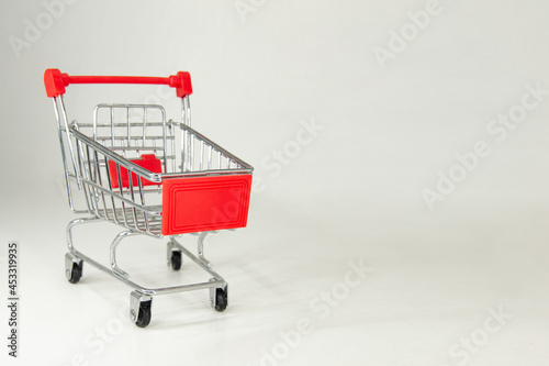 Metal shopping cart with red plastic. White background. Space for text. Horizontal photography.