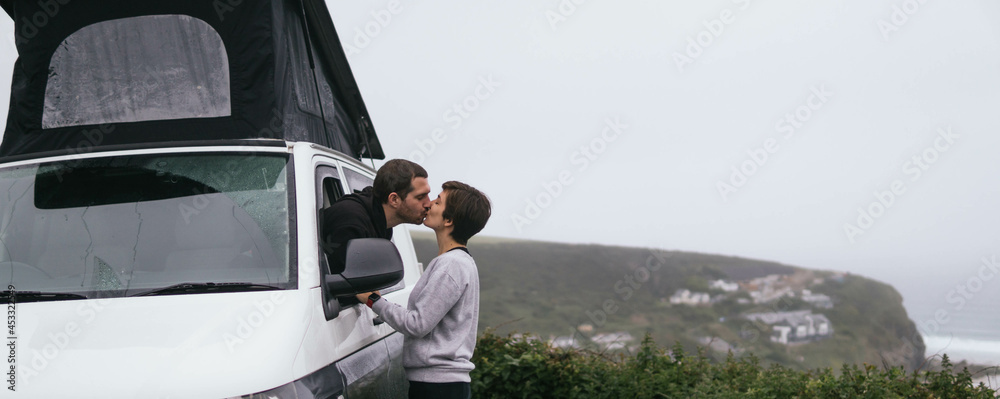 Young couple kissing while travelling in a van around the world. Simple things. Happy romantic couple, nomad travel.