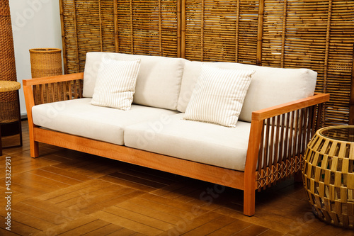 Wood sofa with white seats and pillows, set on a room with bamboo wall © Marcelo Trad Nery