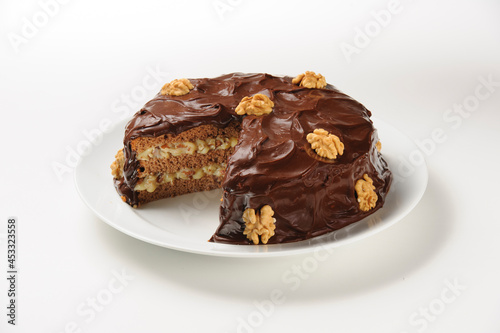 Tasty cake with generous chocolate frosting and dulce de leche filling  with walnuts decoration  isolated