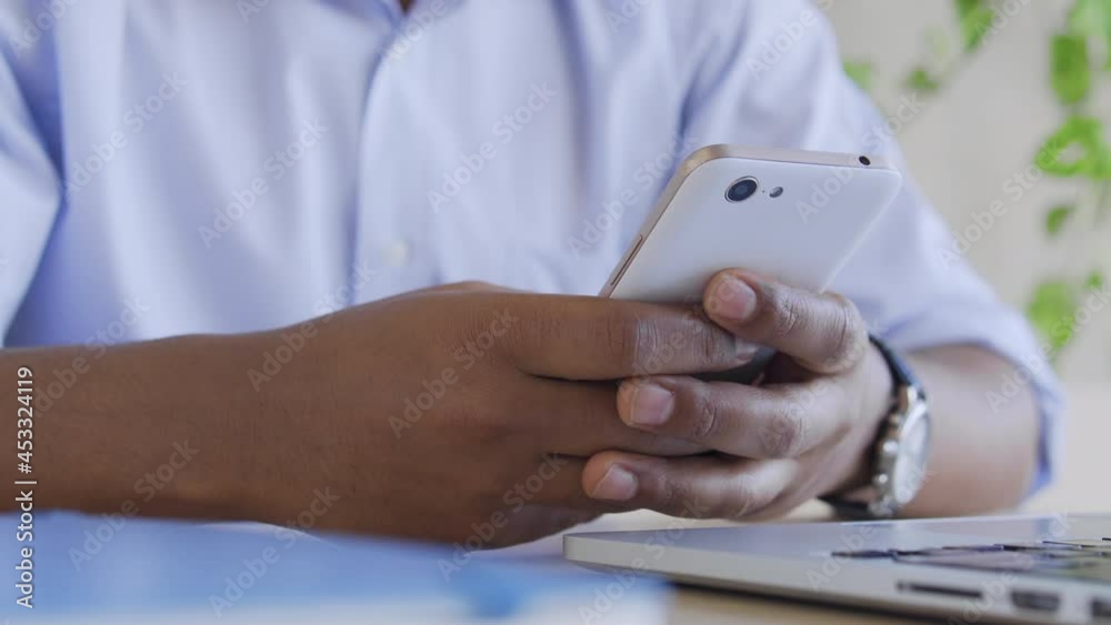Mixed-race man typing on smartphone, chatting in social network during job break Mixed-race man typing on smartphone, chatting in social network during job break