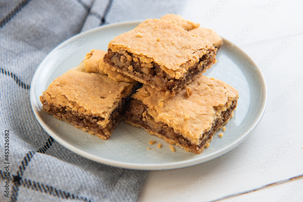 slices of homemade walnut cake from shortcrust pastry on a beautiful plate on a background with a checkered napkin
