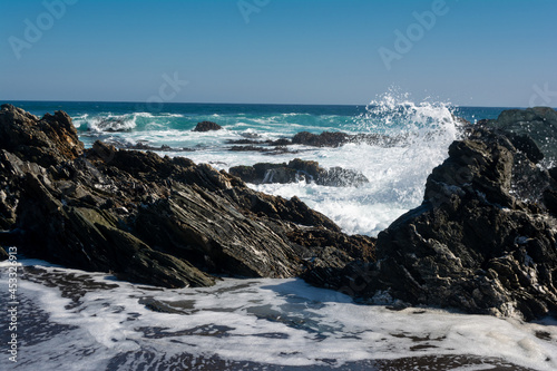 Olas y espuma entre rocas a orilla del mar