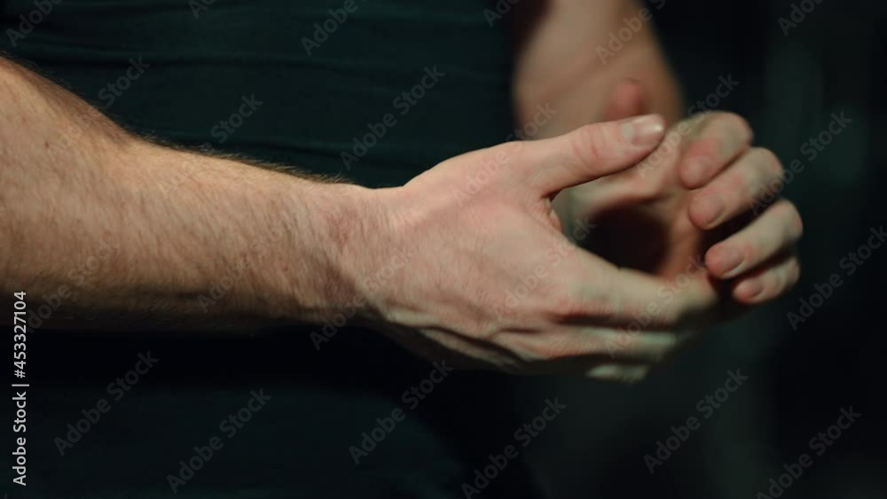 Man rubbing and warming up his hands on dark background. Closeup bodybuilder preparing for workout in gym. Concept of body part Man rubbing and warming up his hands on dark background. Closeup bodybuilder preparing for workout in gym. Concept of body part