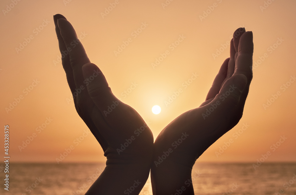 hands reaching out to sky and sea, warm sunset in the palm of hands