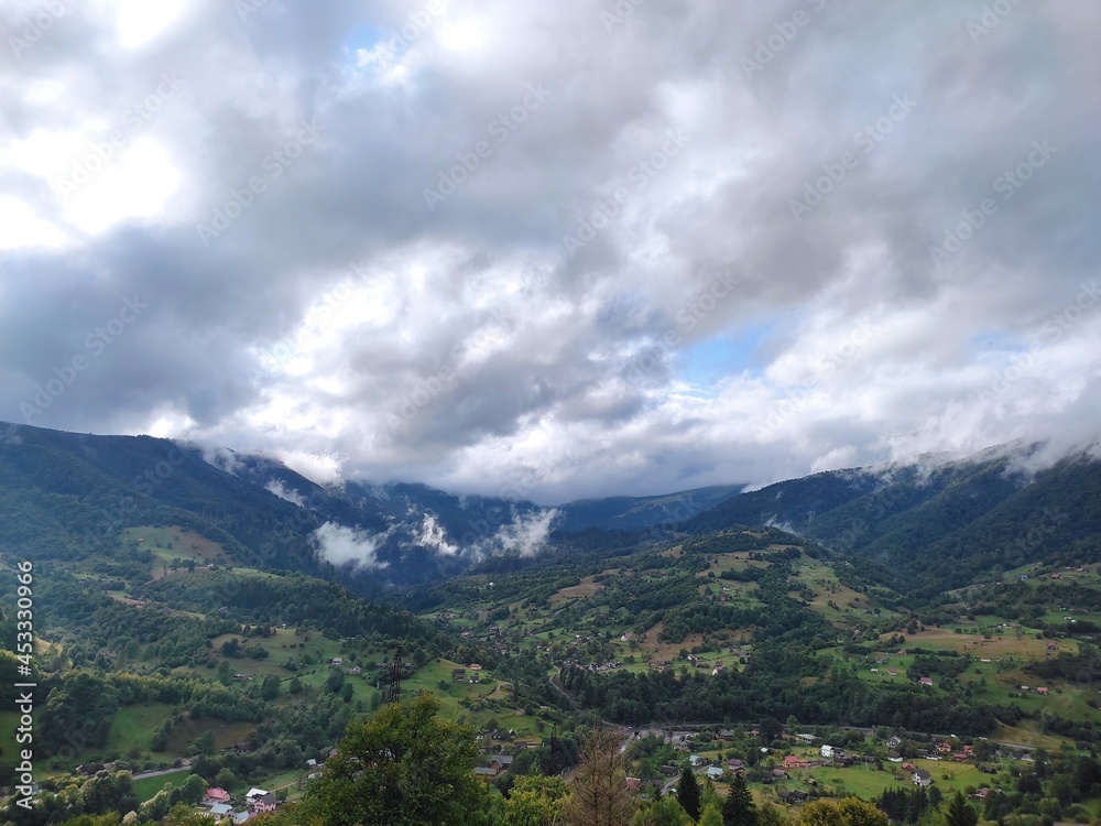 Beautiful landscape overlooking the Carpathian mountains in summer with green grass, trees and sky