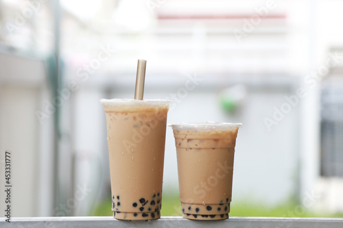 Two cup big and small iced milk tea wih bubble boba fresh and sweet drink Taiwan style put on the steel bar and blur background , food and drink concept