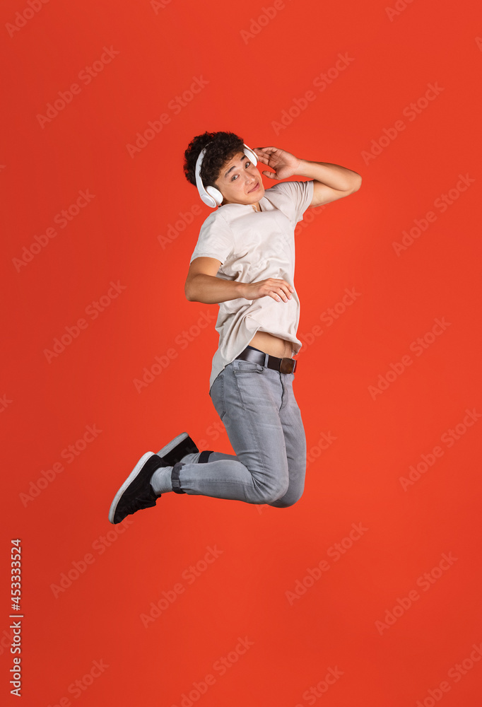 Asian man's portrait isolated over red studio background with copyspace for ad. Concept of human emotions, fashion, beauty, youth