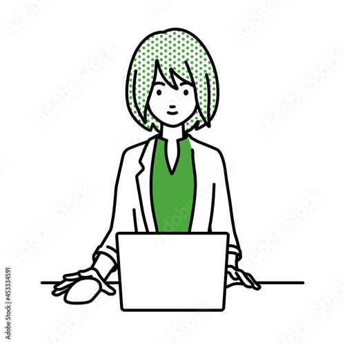 デスクで座ってPCを使っているジャケットの女性