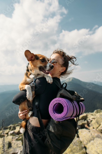 sporty young woman with a dog on top of the mountain