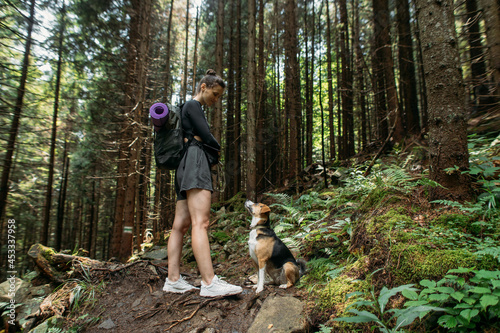 young woman hiking with a dog in the woods