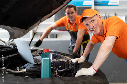 Two mechanic worker working at the garage. Group of professional mechanic examining, repair and maintenance under hood of car at auto car repair service. Car service concept