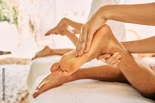 Couple getting foot massage at wellness center during romantic vacation. Foot reflexology, foot massage with oil, close-up