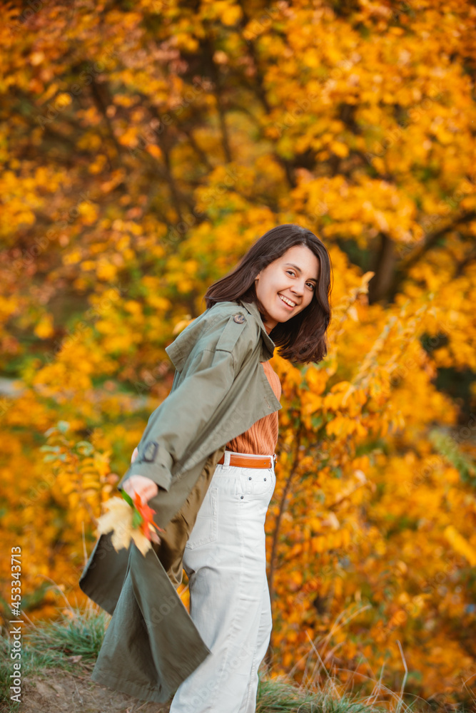smiling woman in front of golden autumn leaves