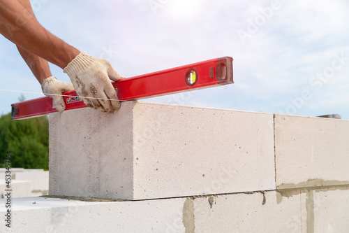 Builder checks the level of the degree of inclination of the blocks. Builder builds a concrete wall made of cement blocks on the construction site of a residential building. Cncept of building a house