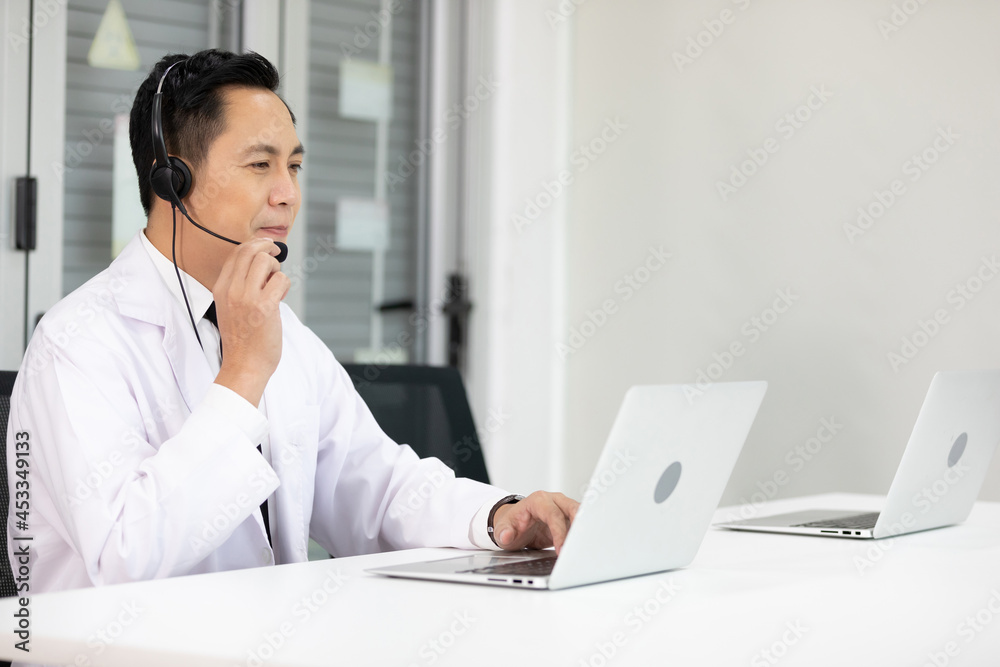 senior doctor wearing headphones and talking with patient or colleague through online video chat from laptop computer