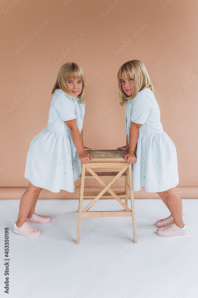 Two beauty twin caucasian blondie girls playing together in the same clothes Two beauty twin caucasian blondie girls playing together in the same clothes