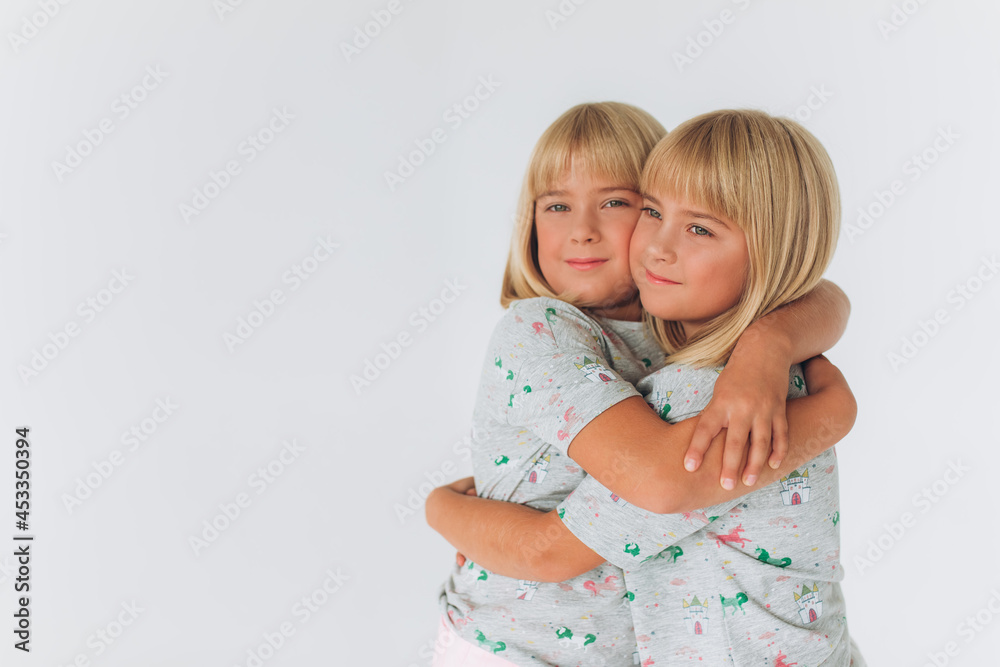 Two beauty twin caucasian blondie girls playing together in the same clothes Two beauty twin caucasian blondie girls playing together in the same clothes
