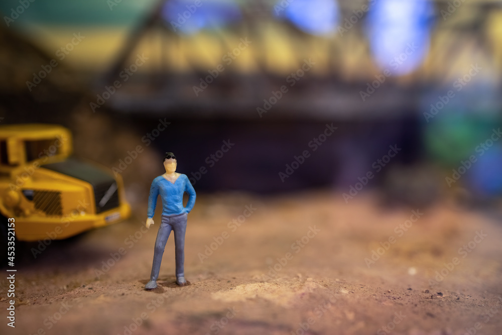 Toy model of male foreman worker standing in front of truck in the construction site. Toy model of male foreman worker standing in front of truck in the construction site.