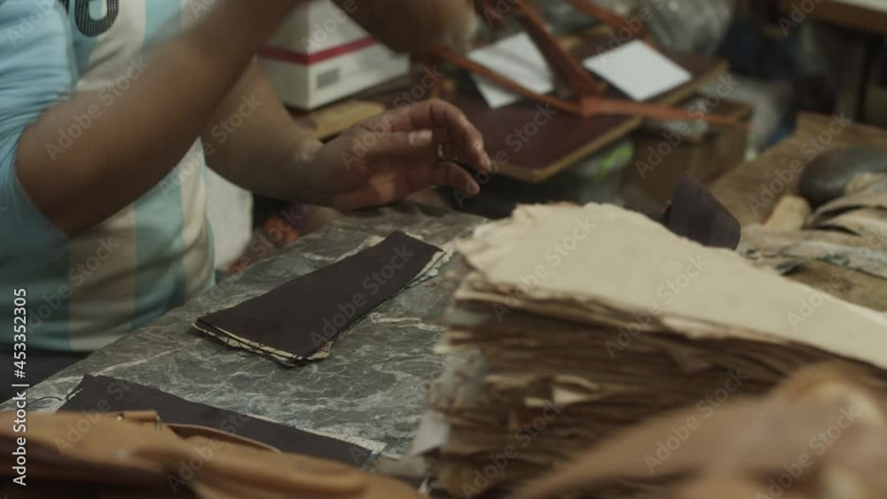 Man working in leather factory. Hammering pieces of leather by wooden tool on stone plate. Traditional handmade process in old factory. Morocco, Africa