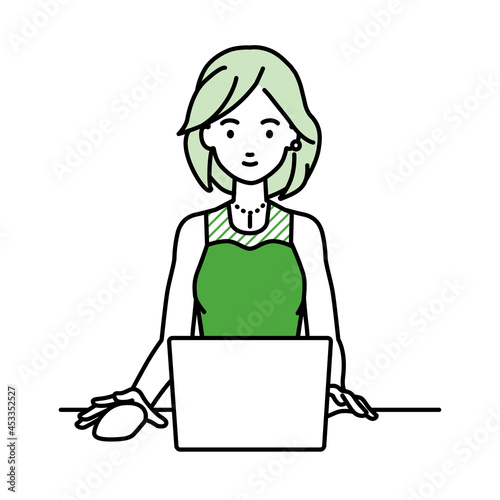 デスクで座ってPCを使っているドレスの女性