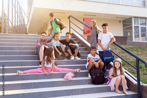 School kids having fun before classes, sitting on the stairs. Back to school