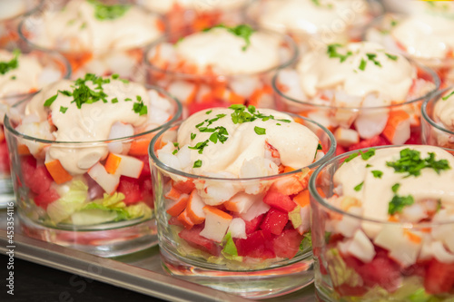 Close up view of glasses of minced prawns with watermelon, crab stick, lettuce, pink sauces, and parsley.