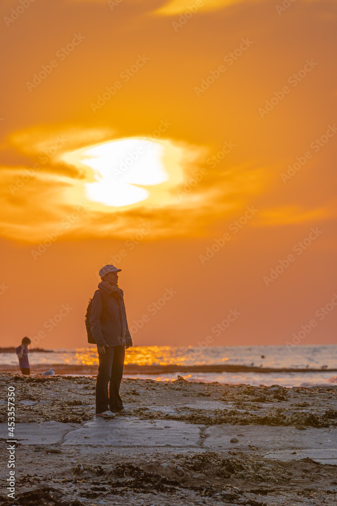 Langrune-sur-Mer, France - 08 04 2021: A woman standing at the beach, looking for the sunset