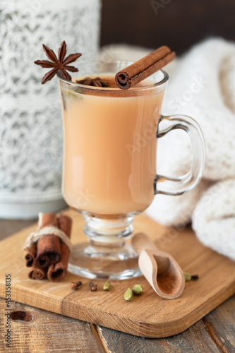 Traditional homemade indian masala chai tea with ingredients. Cinnamon, cardamon, anise, black tea. Hot autumn and winter drink. Aromatherapy, cozy home atmosphere. Wooden background.