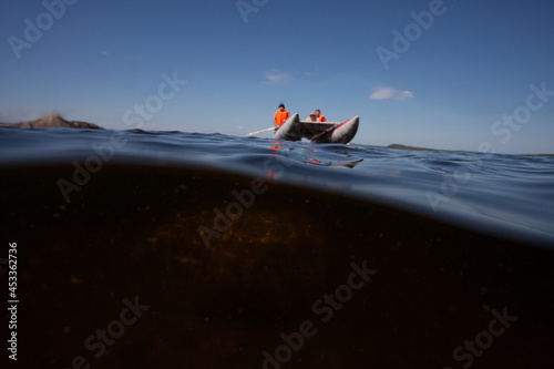 Catamaran boat sails over an underwater rock underwater photo in half of the water scandinavia