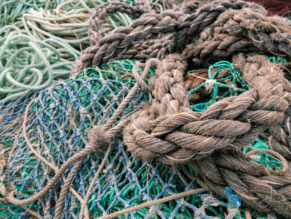 Old and unraveled fishing ropes and nets grouped together for review before the fishermen set out to fish forming an abstract background marin