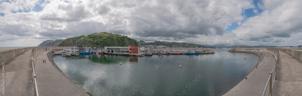 Overview of the fishing port of Laredo with the boats docked next to the San Martín fishermen's association and the marina and the village in the background