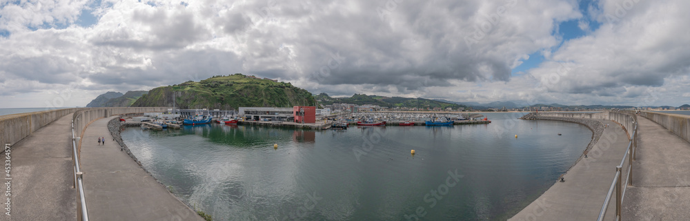 Overview of the fishing port of Laredo with the boats docked next to the San Martín fishermen's association and the marina and the village in the background Overview of the fishing port of Laredo with the boats docked next to the San Martín fishermen's association and the marina and the village in the background