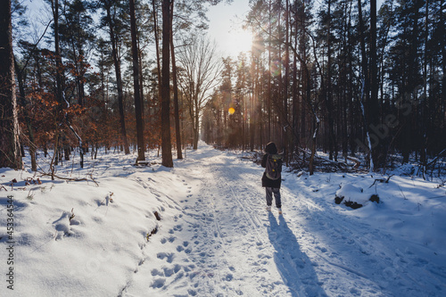 hiker and walker in forest in winter time with snow and ice, wonderful daylight and sun.