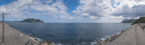 Panoramic of the rock of Santona and the Cantabrian Sea with a spectacular blue sky covered with cumulus clouds with the sea disappearing towards infinity from the port of Laredo