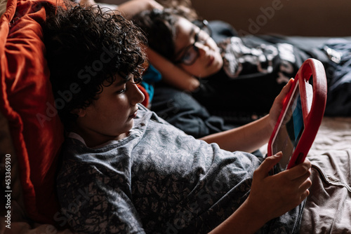 Niños en cama con una tableta digital usando tecnología