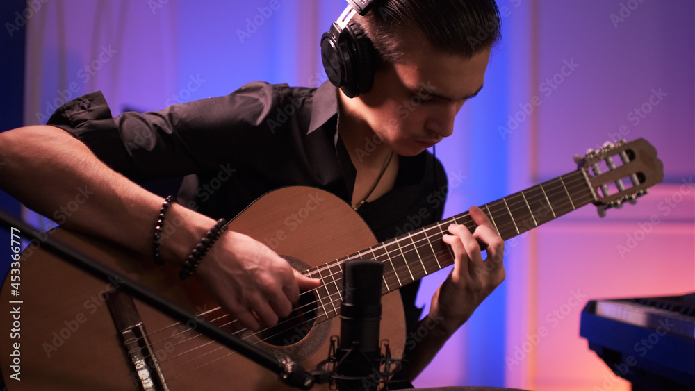 Obraz premium Musician in a headphones records his composition in a music Studio using professional audio microphone.