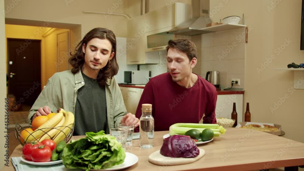 Two young friends are sitting at the table and talking to each other Two young friends are sitting at the table and talking to each other