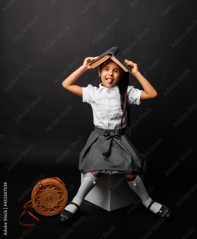 Book roof over her head. Little girl holding a textbook on her head ...