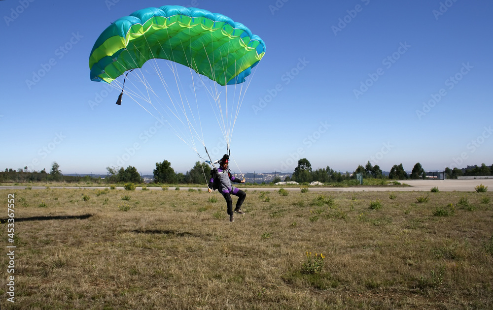 Skydiver landing his parachute on the ground - obrazy, fototapety, plakaty 