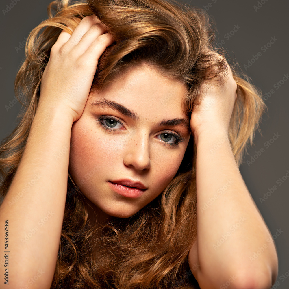 Closeup portrait of an young adult girl with long curly hair. Photo of a fashion model posing at studio. Pretty young woman with long brown hair looking at camera. Beauty portrait. Closeup portrait of an young adult girl with long curly hair. Photo of a fashion model posing at studio. Pretty young woman with long brown hair looking at camera. Beauty portrait.