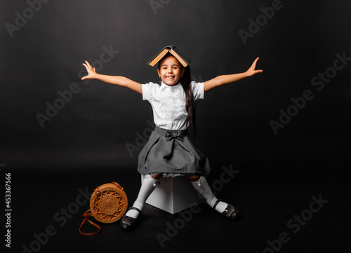 Принти на полотні schoolgirl brunette with a book on her head emotionally raised her hands up