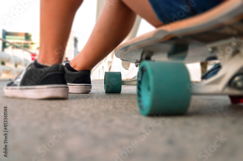 Photographic shot from the ground of a skateboard cruise with a seated girl. Transport, sport and street concept photo