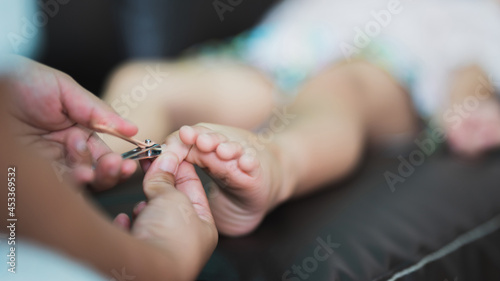 Foot and toe pedicure for baby by hand mom hold nail clippers to cut pedicure for clean with love and care. Body part. Family time.